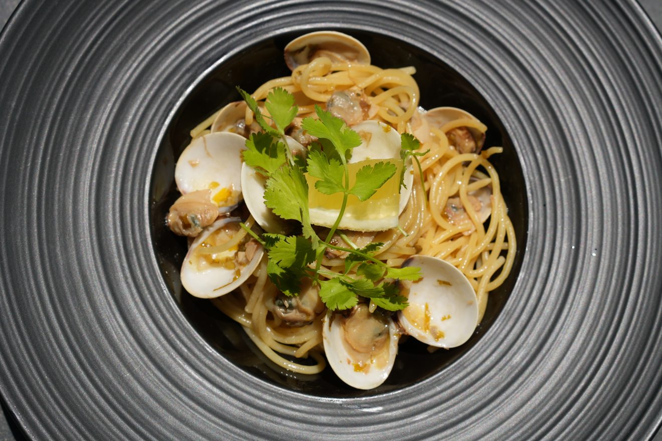Massa fresca do GIO com amêijoas em prato escuro