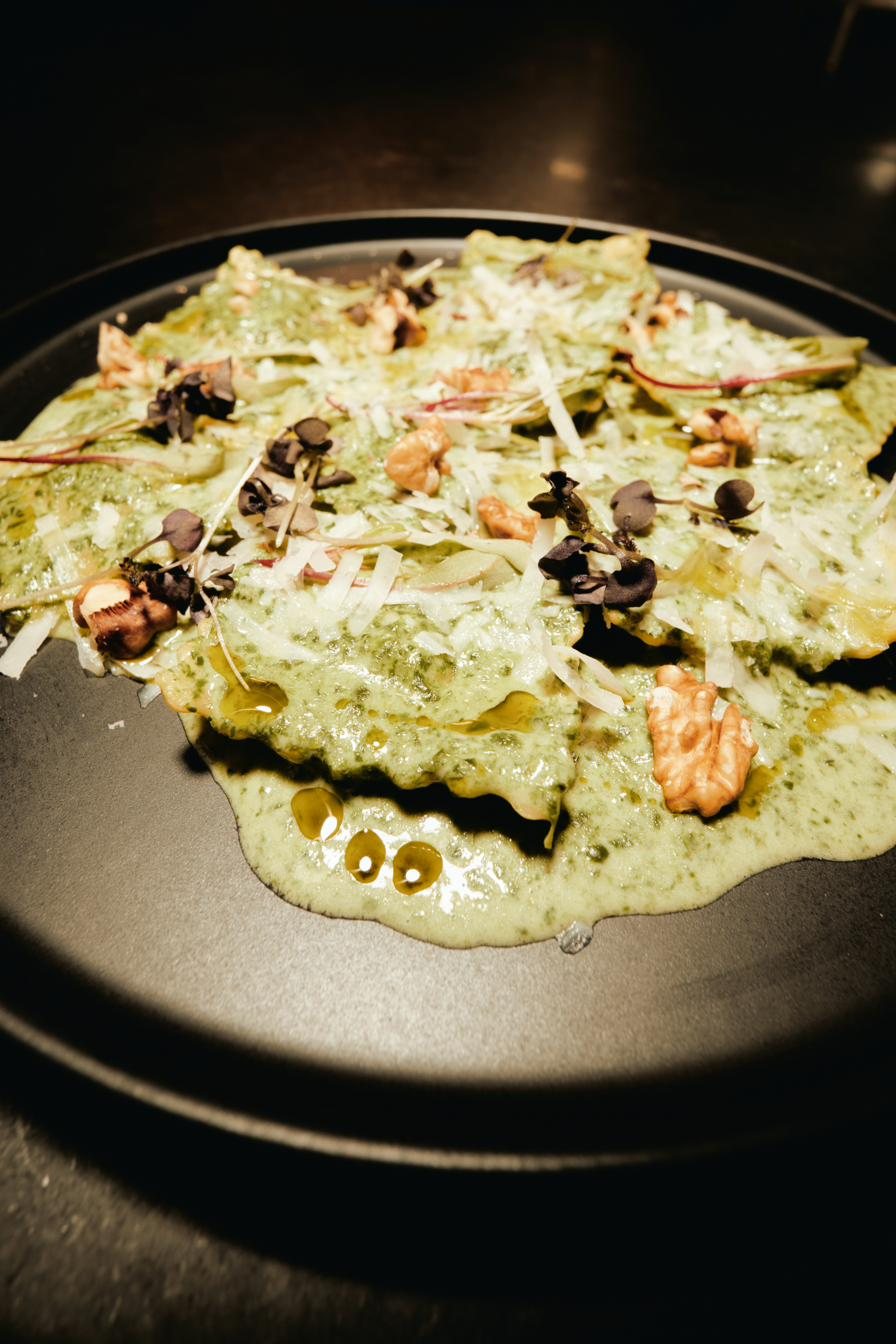 Ravioli com pesto e parmesão em prato preto