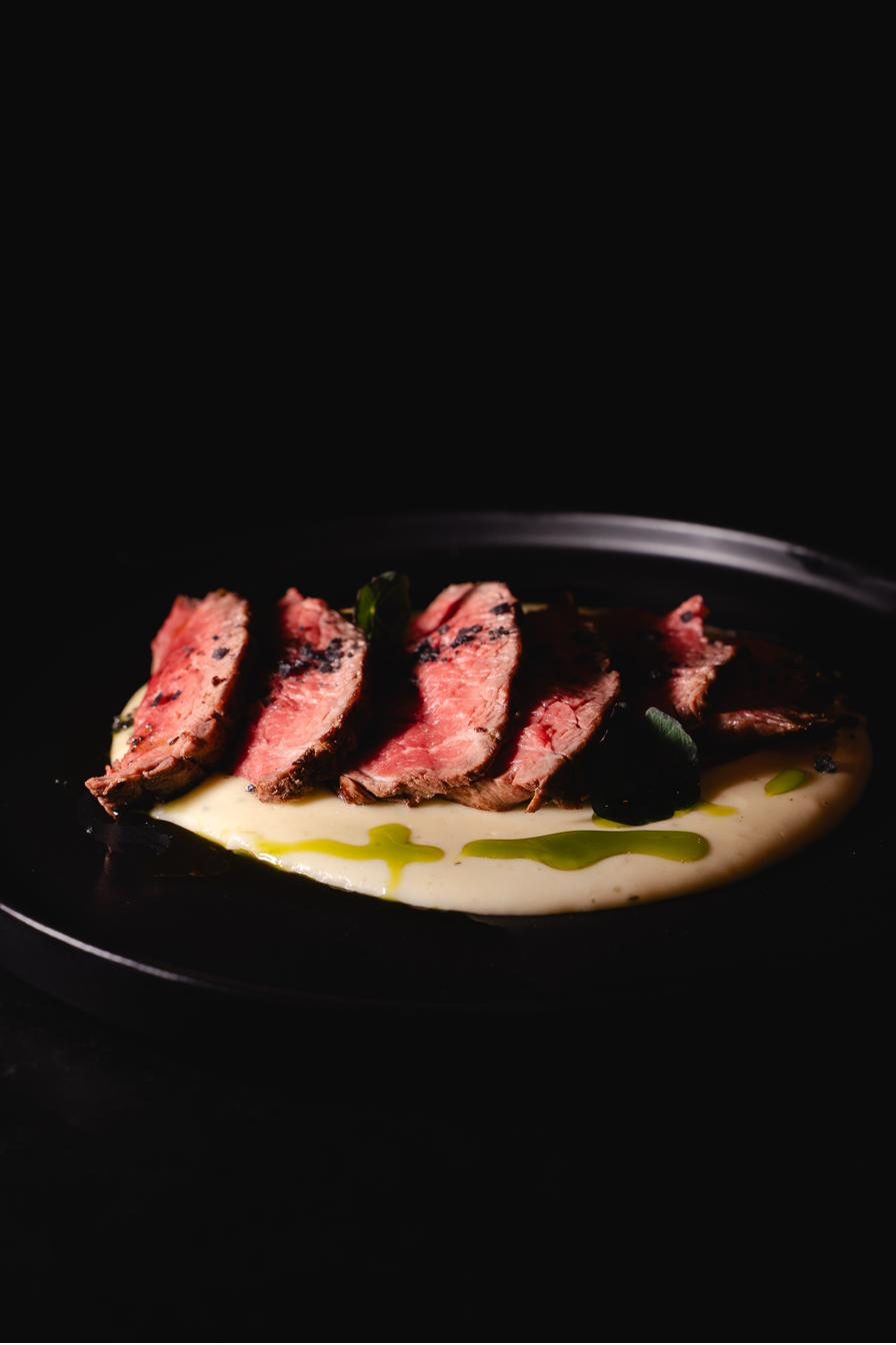 Tagliata de novilho fatiada sobre creme